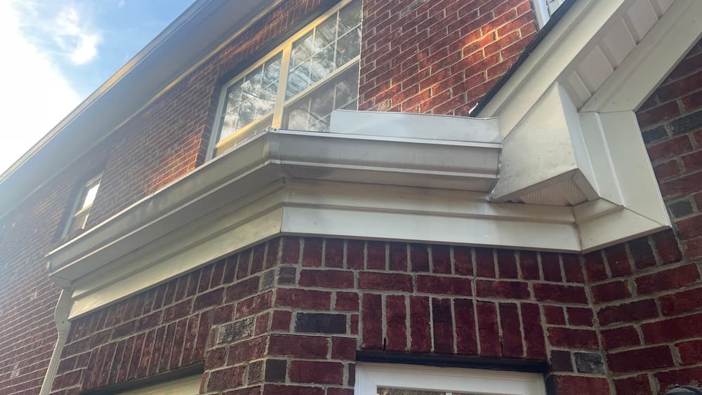 Brick house exterior showing a dormer with new white trim and gutter
