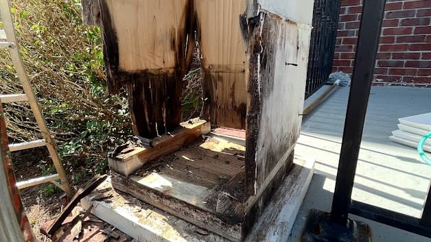 Rotted wood column base at a brick porch cut away and exposed for repair