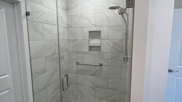 Tiled walk-in shower with a glass door and a built-in niche