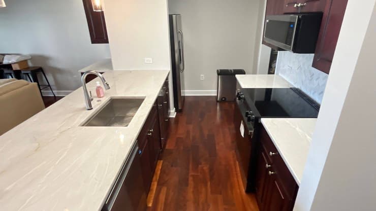 Galley kitchen with dark cabinets, quartz counters and a stainless sink