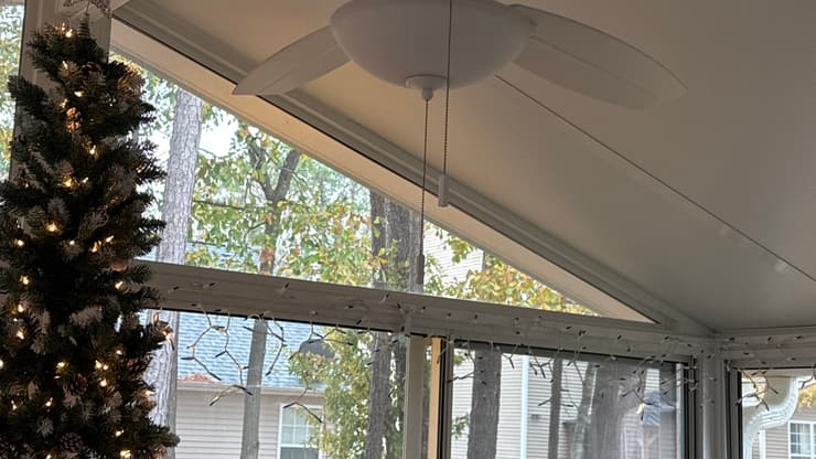 Screened porch with a ceiling fan looking out over a fenced yard