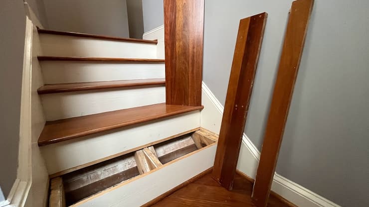 Hardwood stair treads partly installed with two finished boards leaning against the wall