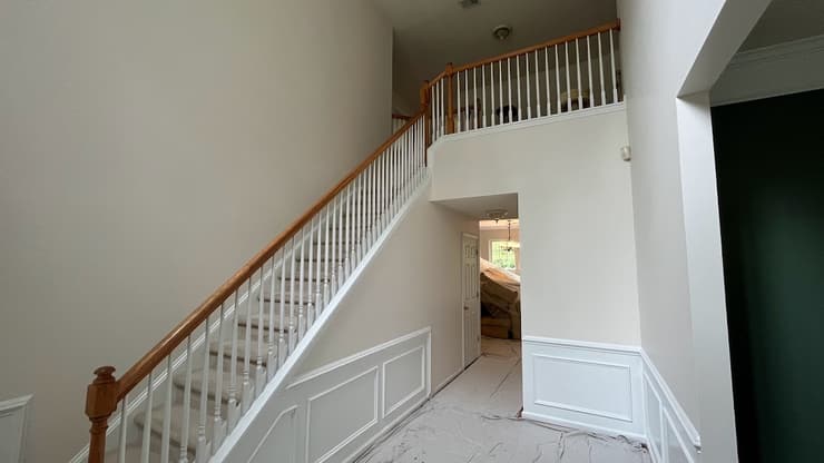Two-story entry with a staircase, white balusters and wainscot paneling