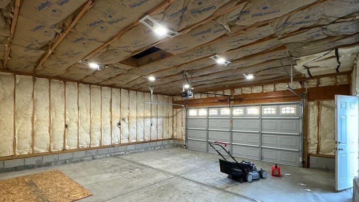 Garage interior with exposed wall insulation and new lighting overhead
