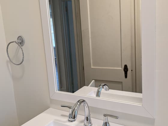 Bathroom vanity with a white top, chrome faucet and a large framed mirror