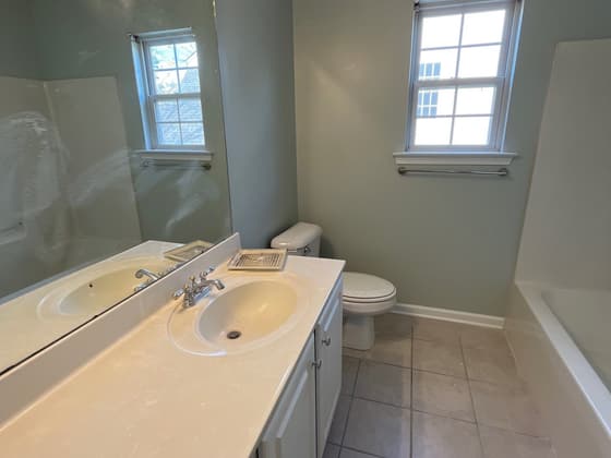 Bathroom with a double vanity, cultured marble top, toilet and window
