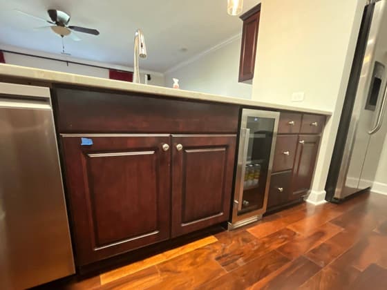 Kitchen with dark cabinets, a glass front cabinet and a wood floor