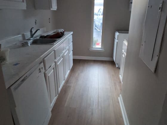 Kitchen with white cabinets, a window over the sink and plank flooring