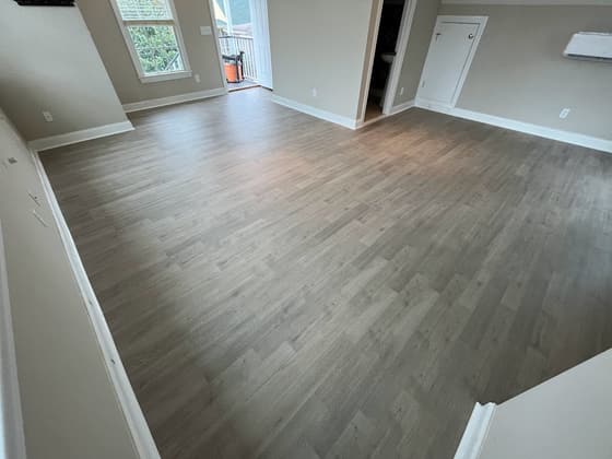Plank flooring installed in a room with white baseboards and a window