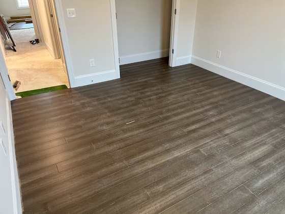 Wood-look plank flooring installed through a doorway into a bedroom