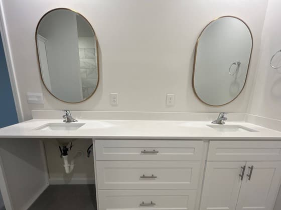 Double vanity with two oval mirrors and white cabinetry