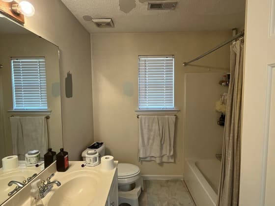 Bathroom before renovation with an older vanity, tub and shower curtain