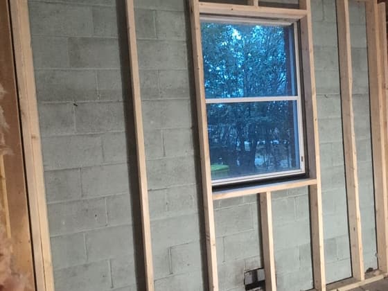 Interior wall stripped back to block and studs around a window during renovation