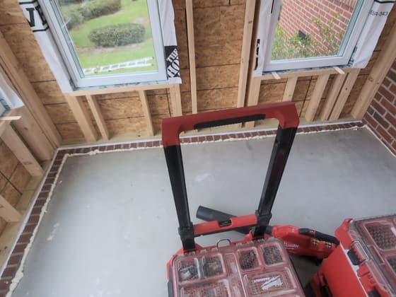 Flooring installation in progress with a red tool case in the doorway