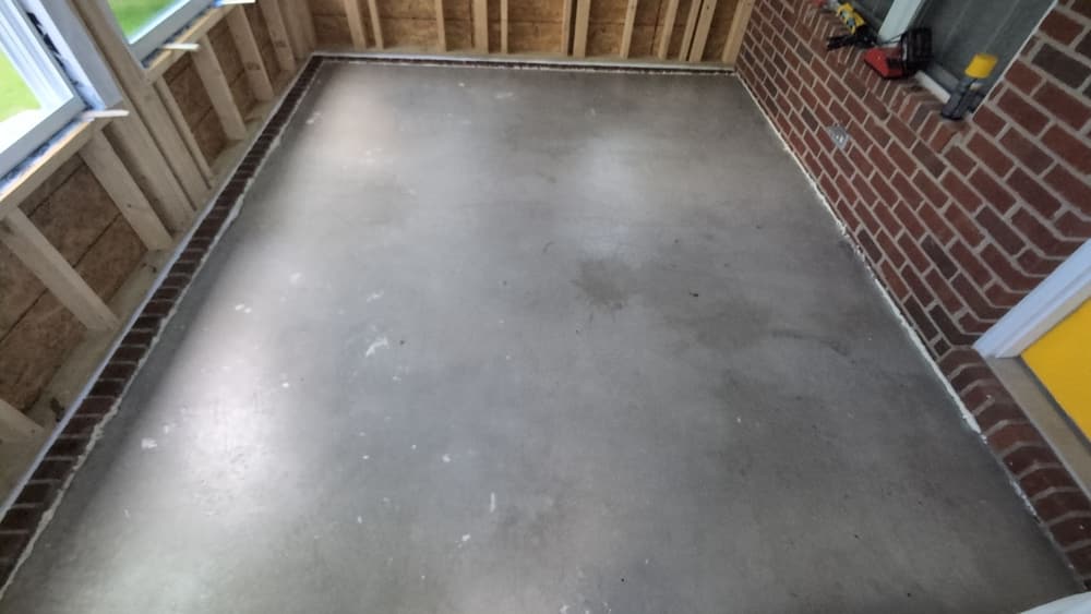 Bare concrete slab on a covered brick patio prepared for a build