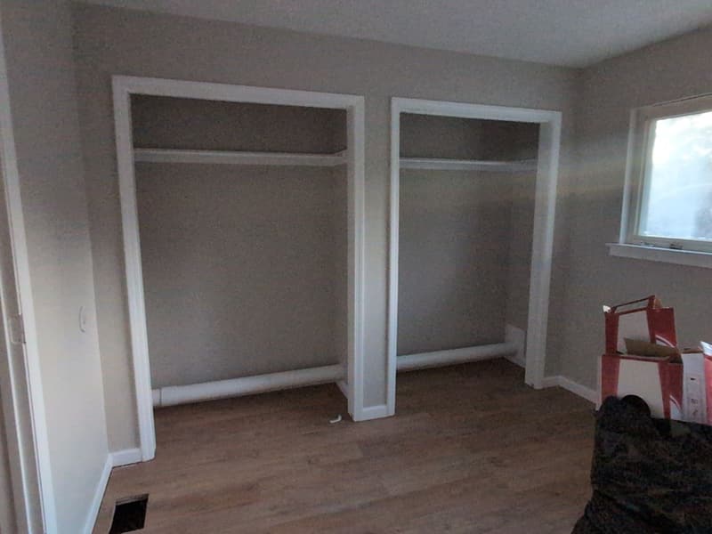 Two framed closet openings built into a bedroom wall above new plank flooring